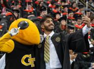 Graduation photo, student taking a selfie with Georgia Tech mascot, Buzz.