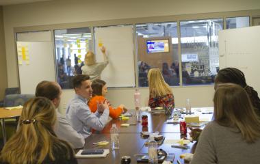 OUE staff sit around a table near a whiteboard